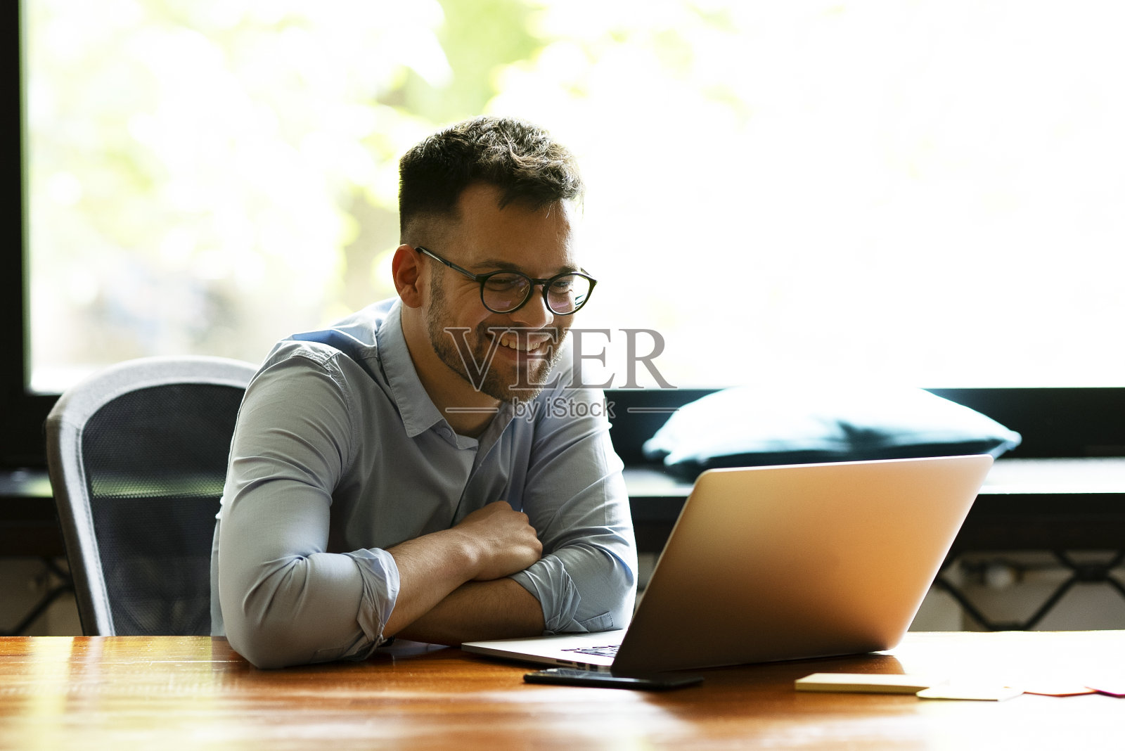 一个微笑着的年轻人正在办公室里做项目。照片摄影图片