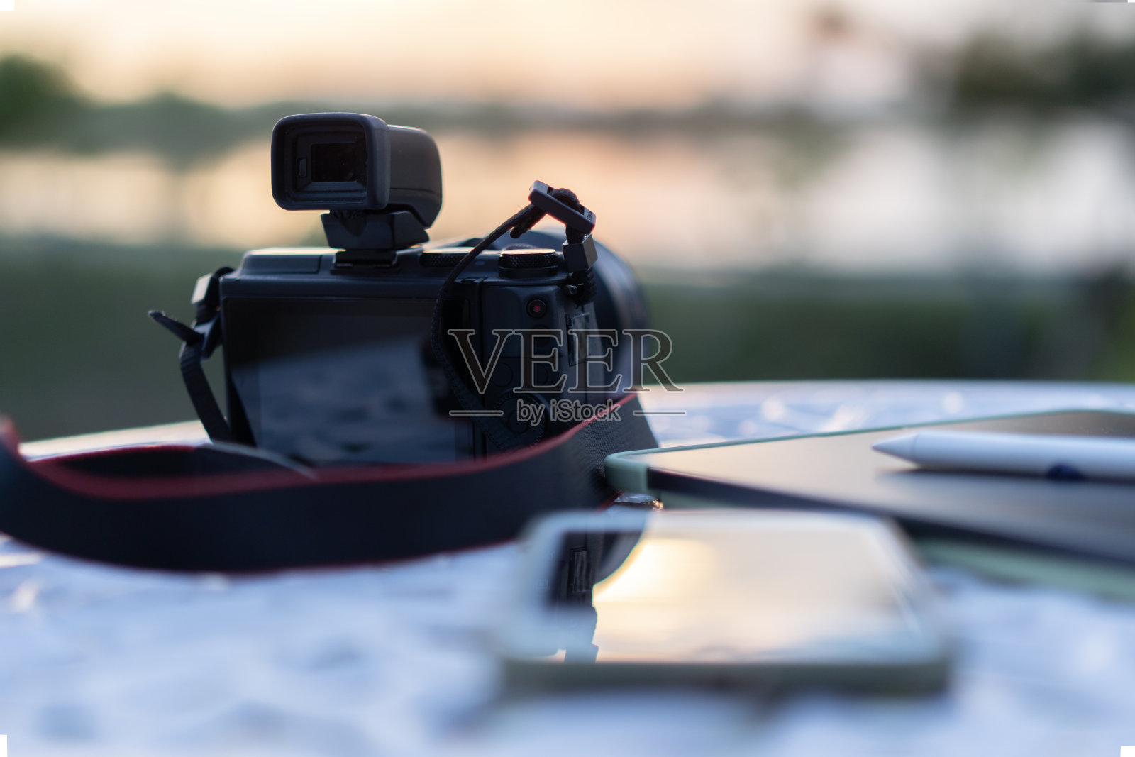 白色花园桌上的旅行摄影器材，背景是模糊的河流景观。照片摄影图片