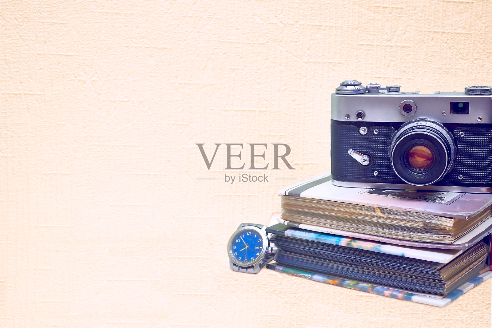 旧的老式胶片照相机与相册和手表孤立在淡粉色照片摄影图片