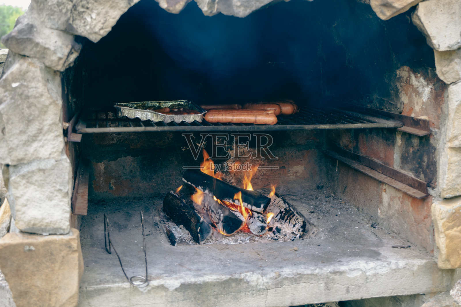 柴火烤架用大石砌成，在花园里烧烤。照片摄影图片