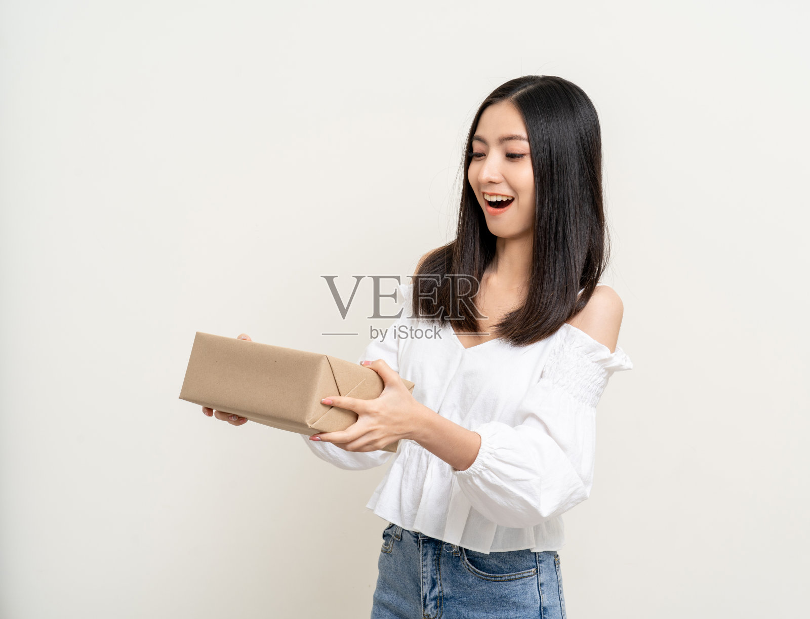 年轻、兴奋、美丽的亚洲女人拿着包裹纸板站在孤立的背景上。兴高采烈的女士拿着一大堆包裹箱，从快递公司收到网上购物的申请照片摄影图片