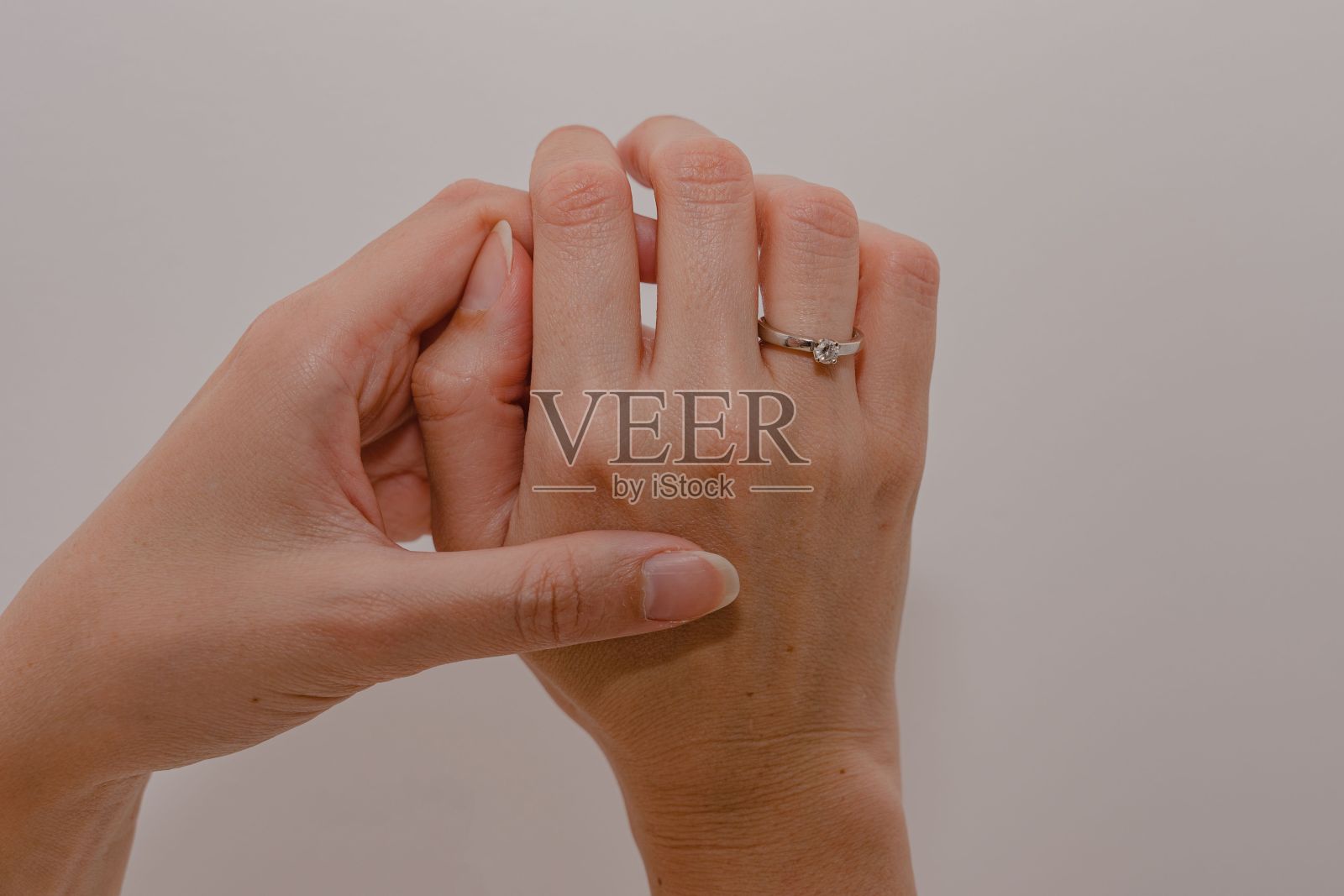 一名女子的双手展示着白底上闪闪发光的订婚钻戒。照片摄影图片