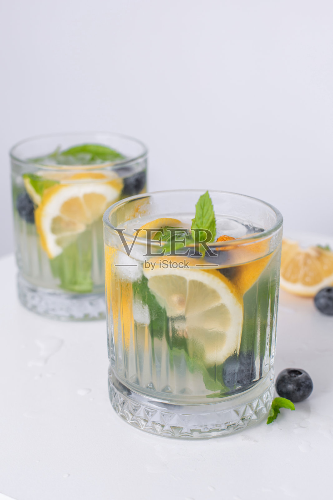 杯子里的柠檬水和白色背景上的柠檬。夏日清凉饮料。柠檬排毒水照片摄影图片