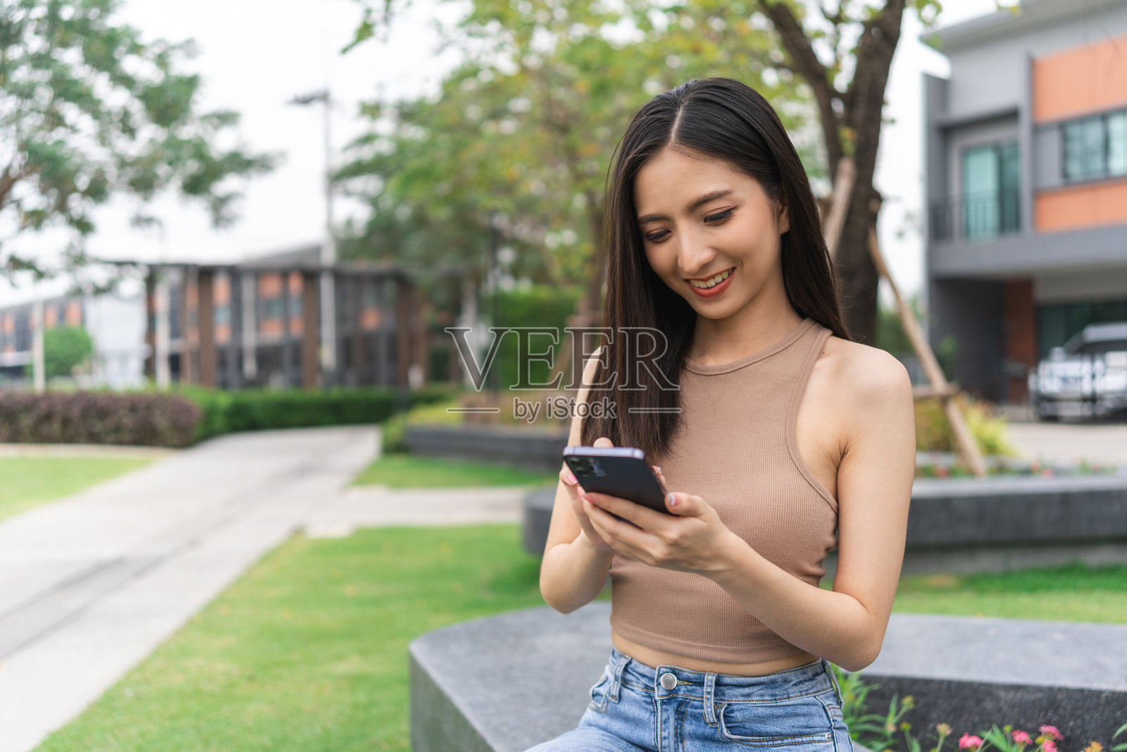 美丽的年轻女子在智能手机上使用短信的快乐感觉。她在网上购物。她笑得很开心。十几岁的女孩从手机阅读新闻感到兴奋。照片摄影图片
