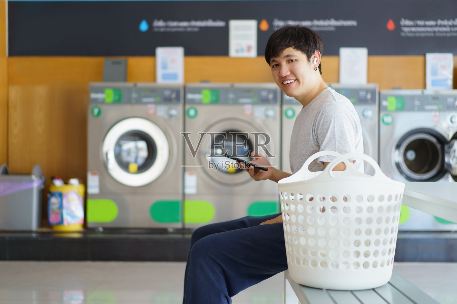 男子在摊贩的洗衣机前洗衣服。照片摄影图片