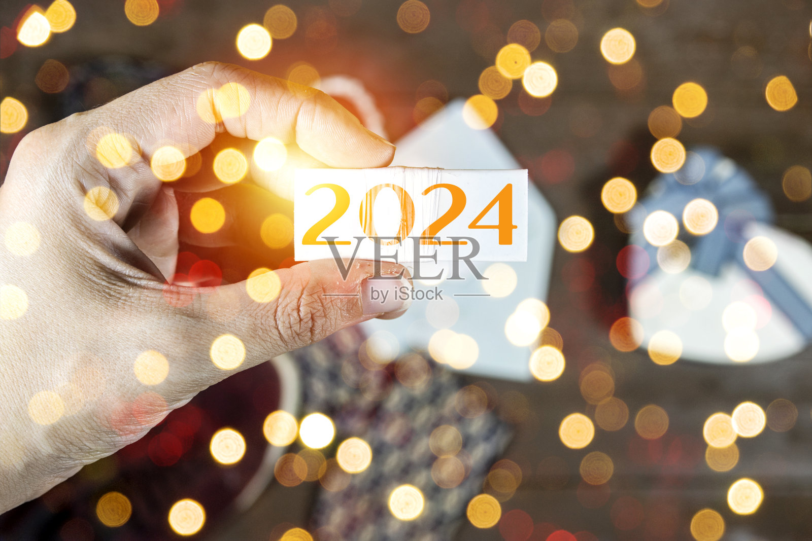 特写手握立方体与2024文字，新年快乐的概念与散景模糊的概念照片摄影图片