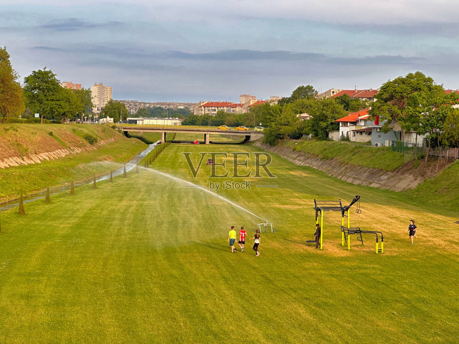 欢快的孩子们在郁郁葱葱的绿地上玩耍，喷水照片摄影图片