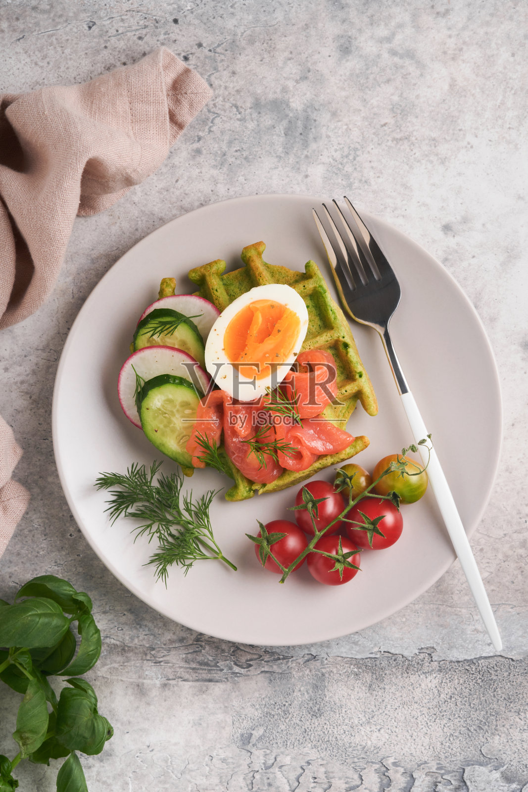 美味的华夫饼。早餐绿色华夫饼，野蒜或菠菜，鸡蛋，西红柿，三文鱼，放在灰色的混凝土桌子上。清淡的晚餐、午餐或早餐。前视图。模拟。照片摄影图片