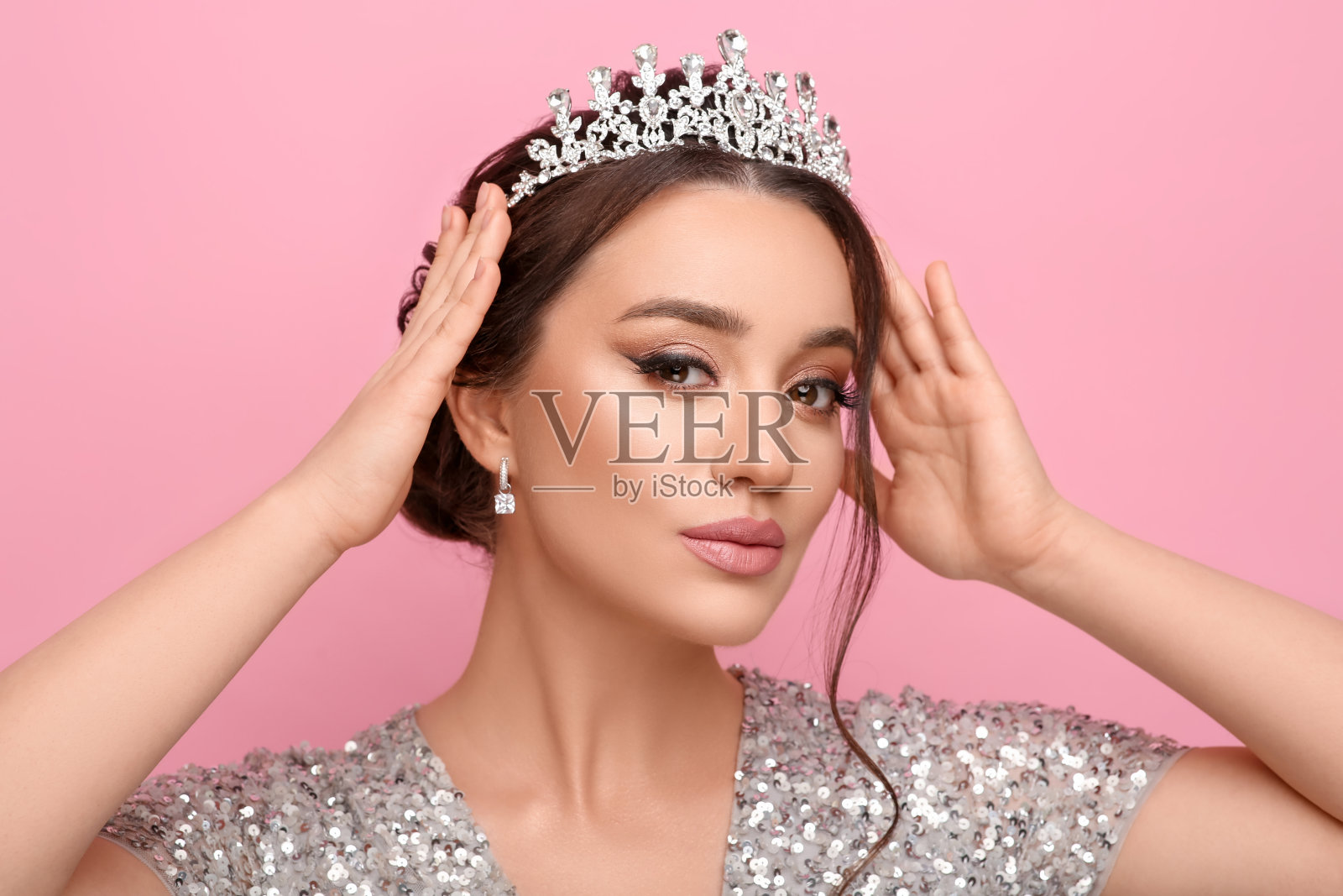 美丽的年轻女子戴着粉红色背景的豪华头饰照片摄影图片