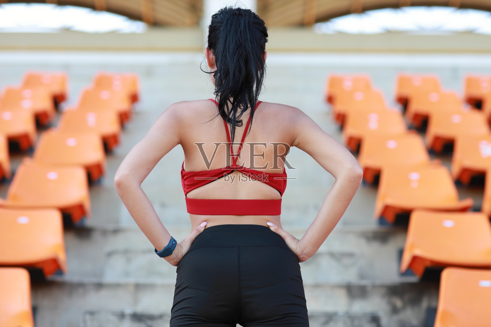 后视图强壮和美丽的亚洲健身女运动员早上跑步和锻炼在体育场，而叉腰和看向别处照片摄影图片