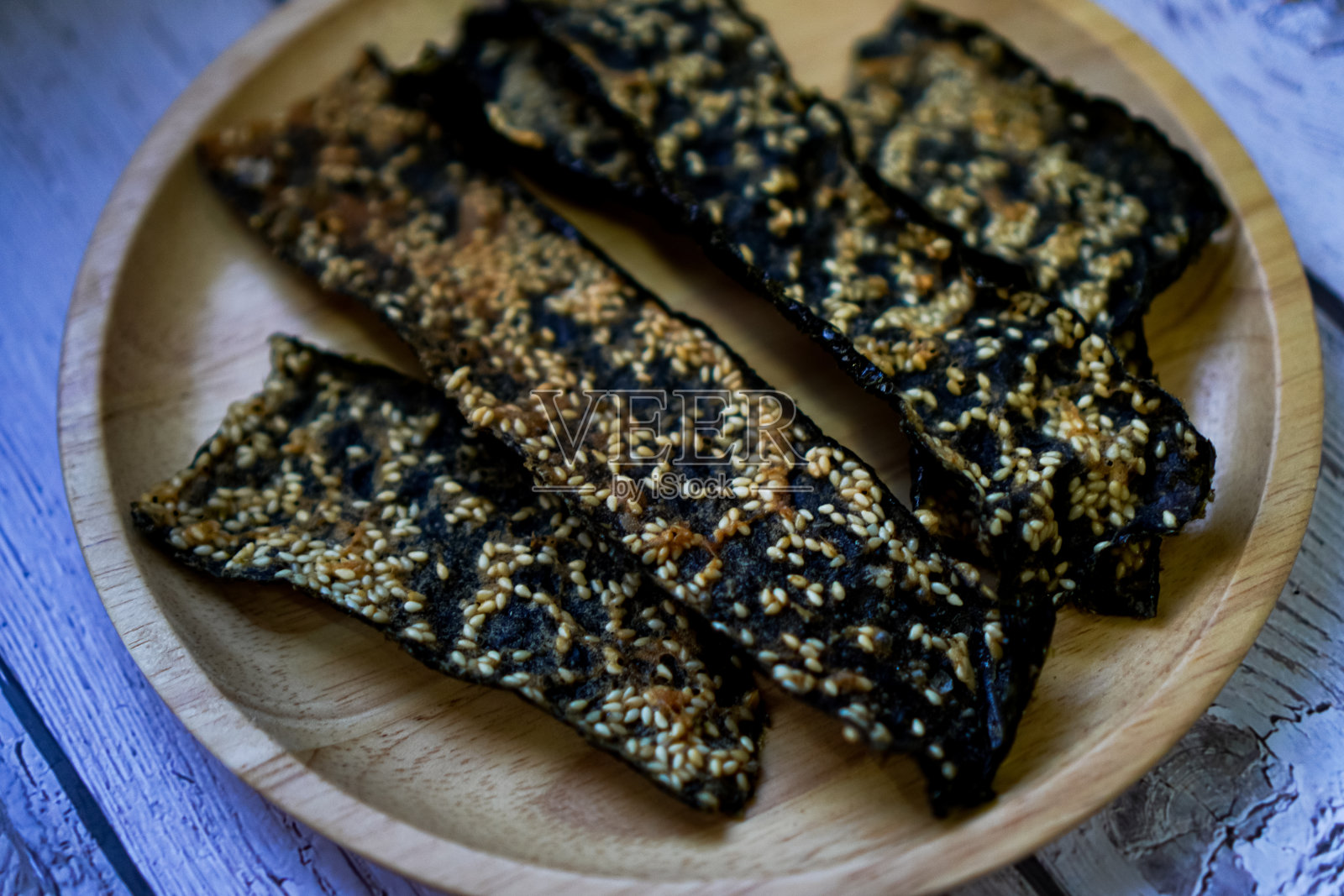 一张特写照片显示，脆脆的炒海藻和白芝麻在一个木制餐具上排成一排。照片摄影图片