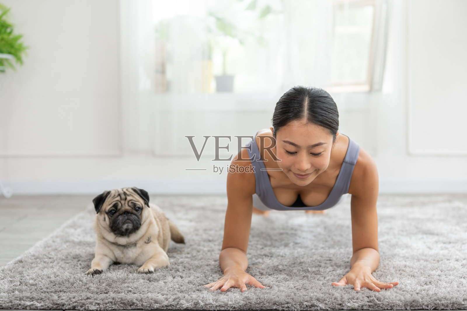 一名亚洲女子和她的哈巴狗在安静的环境中做瑜伽，培养身心的和谐与健康。自我照顾概念。照片摄影图片