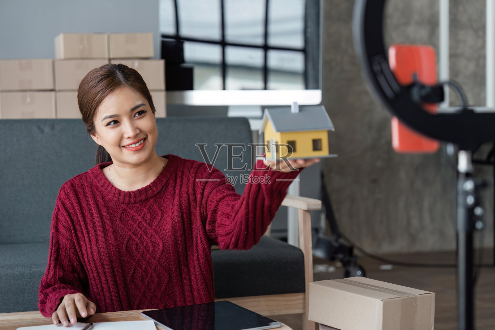 女卖家正在用智能手机在Vlog上直播，并与客户交谈，在社交媒体上销售在线产品照片摄影图片