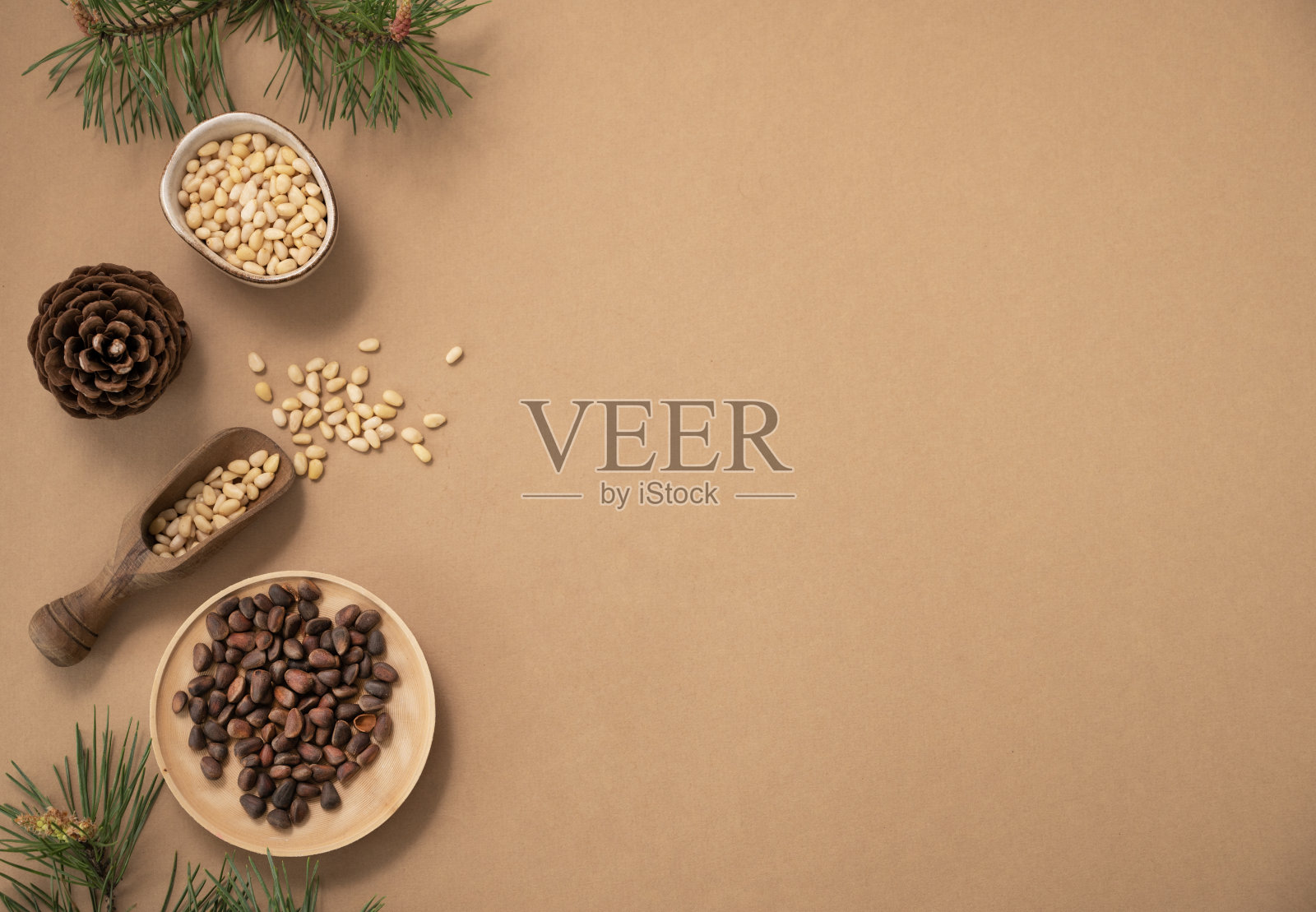 把松子平铺在一个碗和一个木勺里，背景是松针和松果。天然、有机、健康的超级食品和零食的概念。照片摄影图片