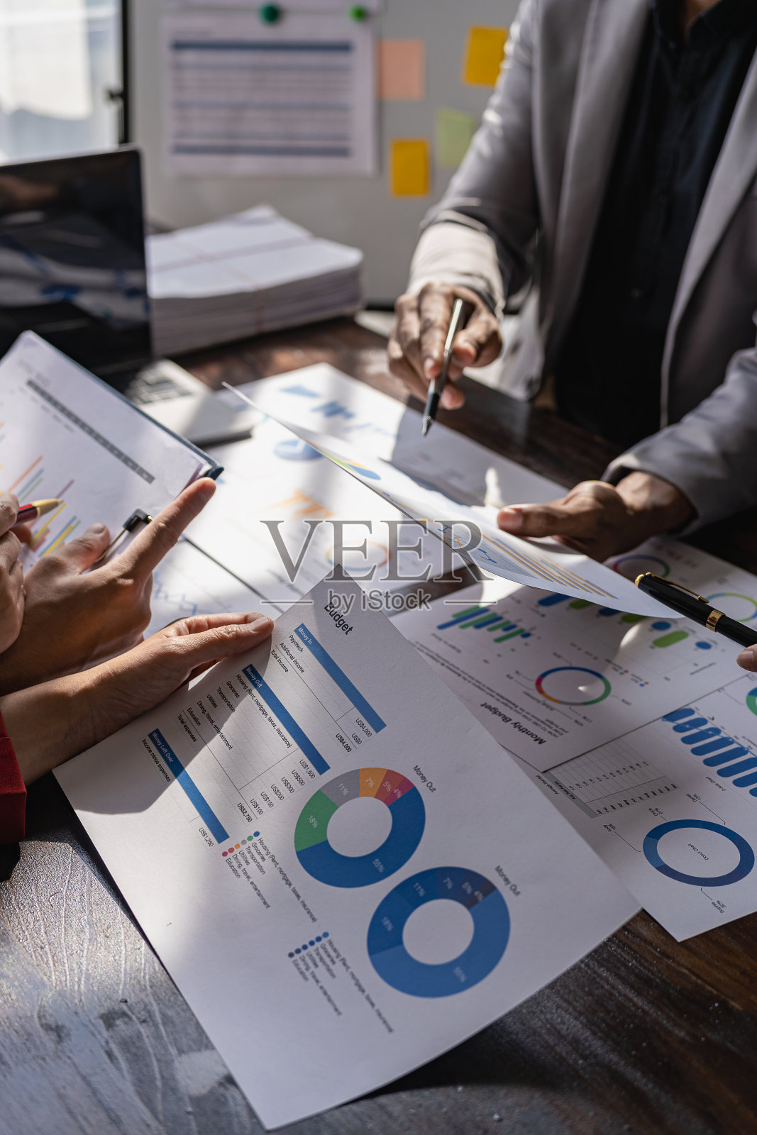 业务团队会议使用计算器使用图表分析业务策略。金融统计坐在办公桌前垂直观看照片摄影图片