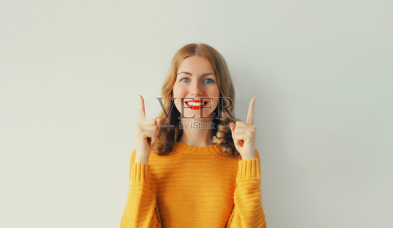 幸福的肖像激动的微笑的年轻女子指着她的手指在白色的背景，空白的复制空间照片摄影图片