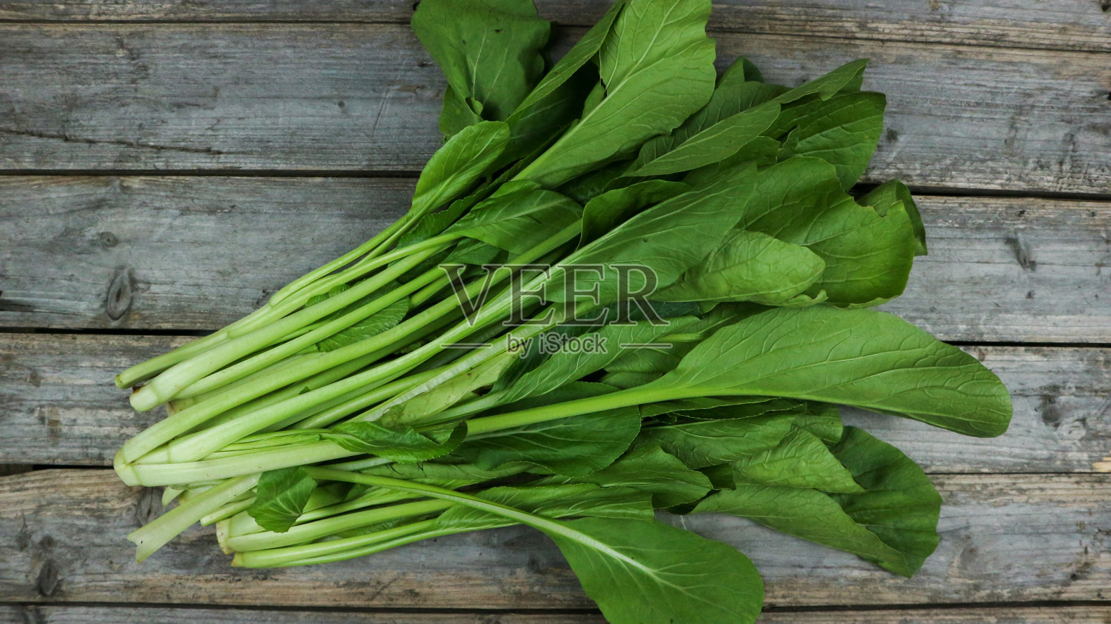 新鲜的芥末，西红柿和胡萝卜蔬菜隔离在灰色的木桌上。照片摄影图片