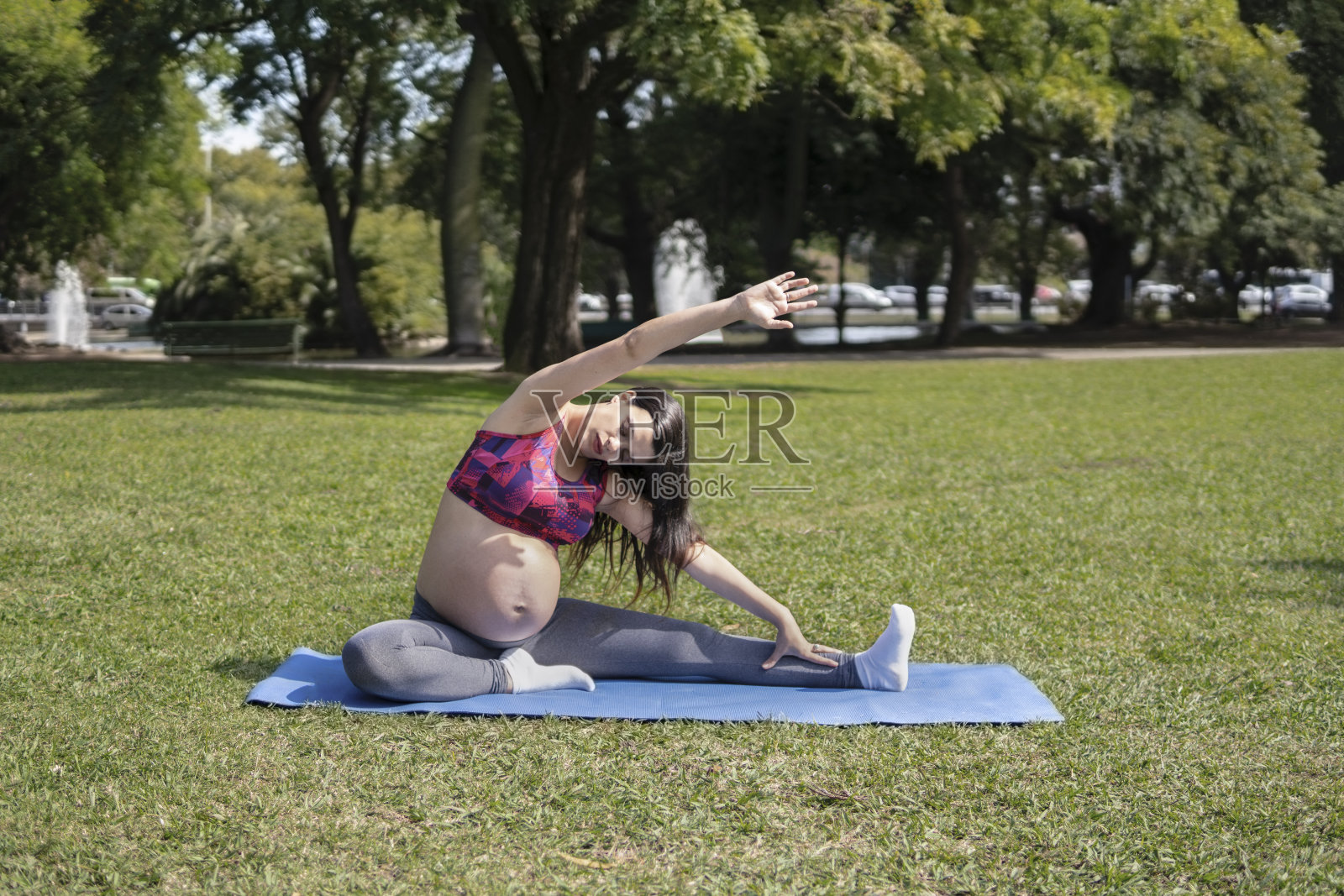 美丽的孕妇在夏季公园做运动。照片摄影图片