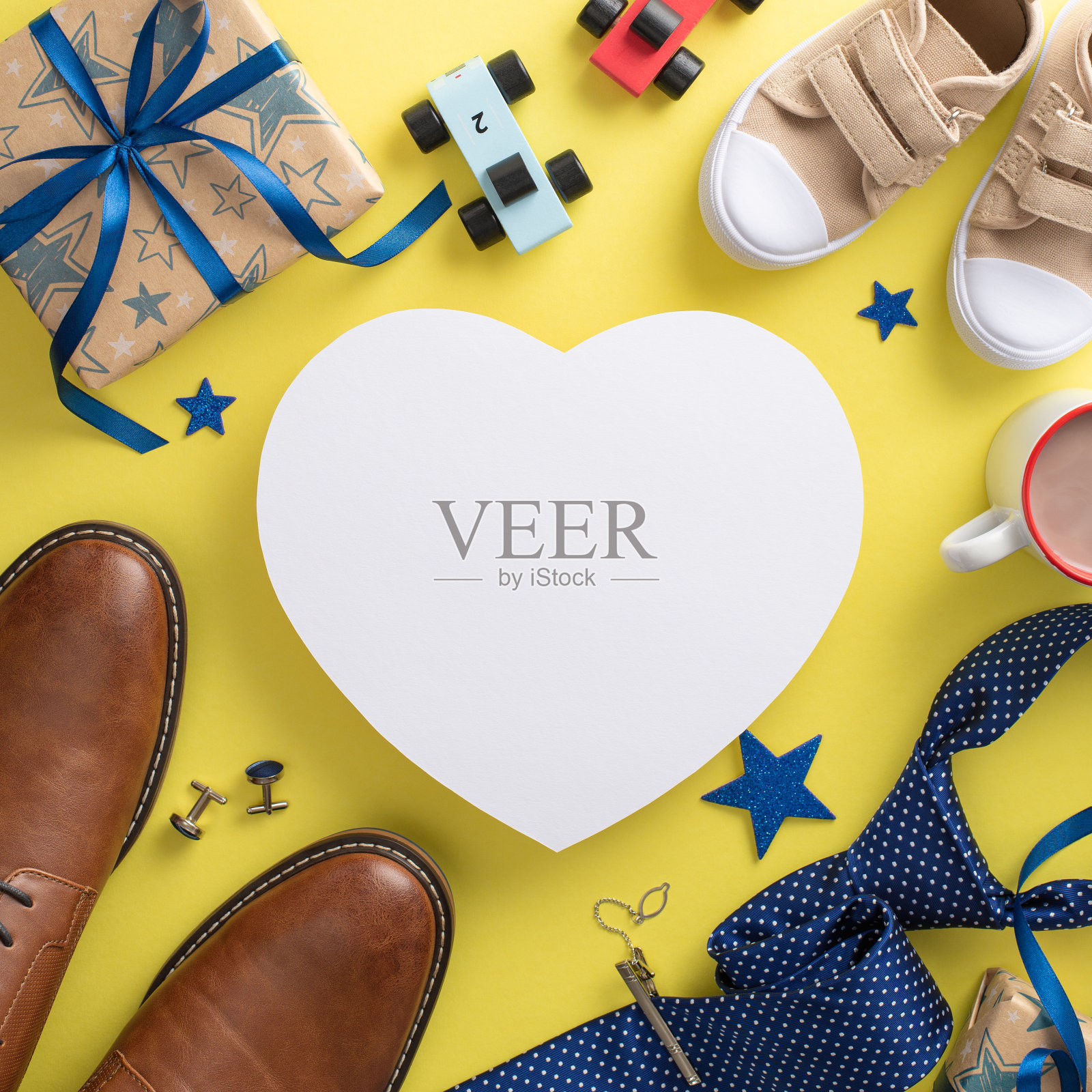 温馨的父亲节场景，儿子和爸爸的鞋子。顶部方形垂直视图运动鞋，鞋子，明星，汽车玩具，可可，领带和礼品盒上的黄色背景与空白的心脏文字或广告照片摄影图片