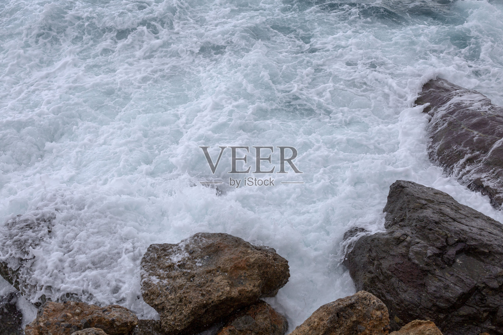 巨大的海浪冲击着岩石，形成白色的泡沫照片摄影图片