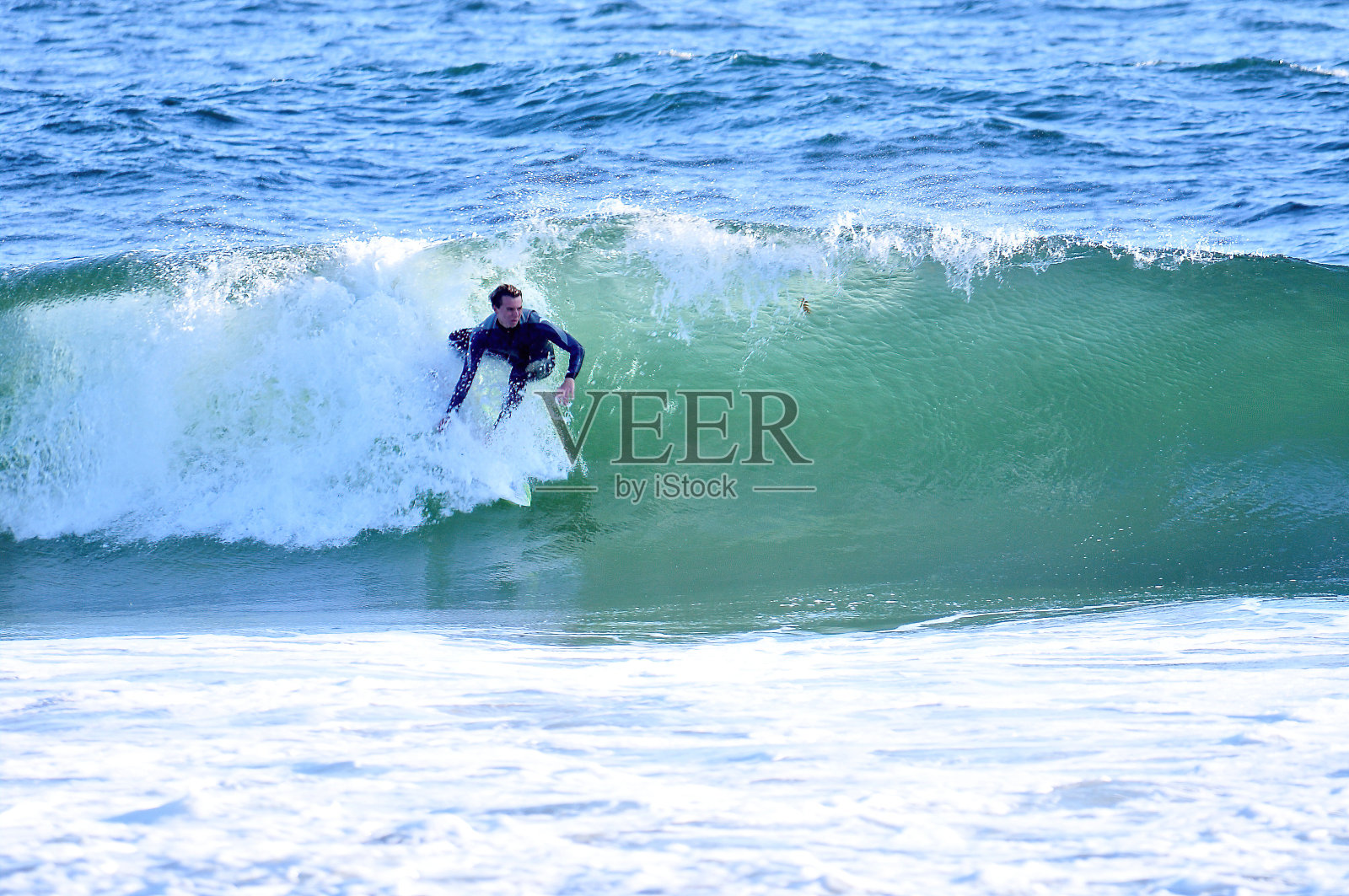 冲浪者冲进蓝色，绿色的巨浪中照片摄影图片