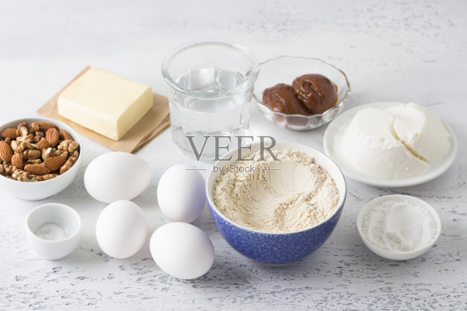 配料:燕麦粉、鸡蛋、水、黄油、奶酪凝乳、煮炼乳、坚果、糖粉、盐，在浅蓝色背景下进行健康的无麸质烘焙照片摄影图片