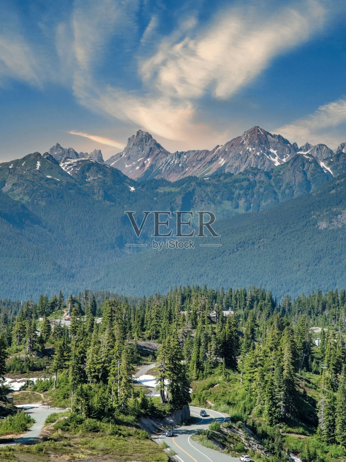 蜿蜒的街道穿过树林，通向远处的山脉照片摄影图片