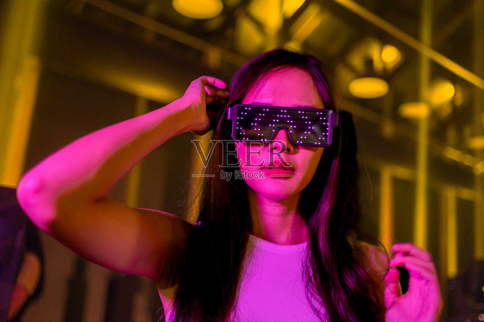 亚洲女人玩游戏与霓虹灯墙的背景。虚拟现实的概念，模拟，游戏和未来技术。照片摄影图片