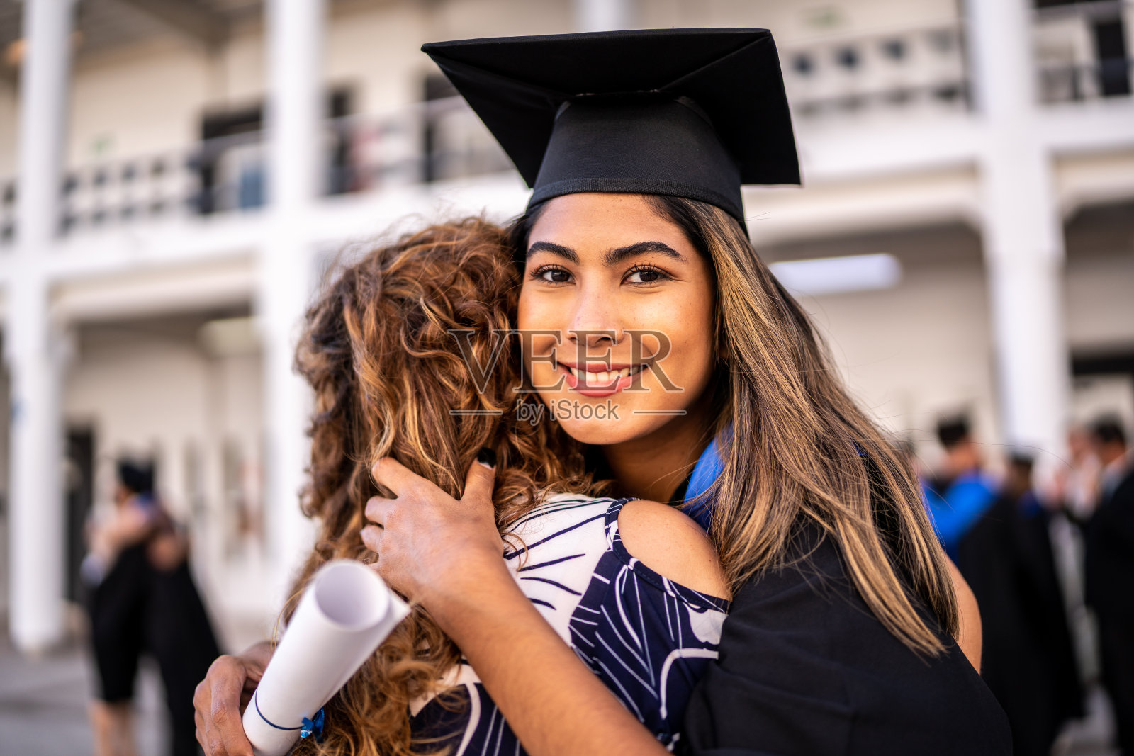 年轻女毕业生在毕业典礼上拥抱母亲的肖像照片摄影图片