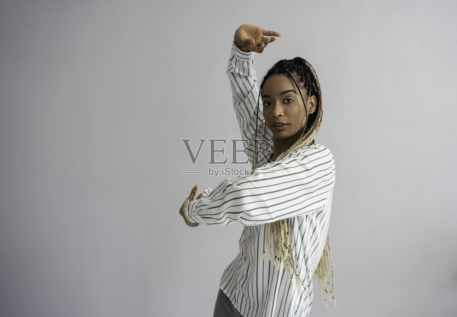 拉丁x世代Z女性在灰色背景上跳舞的肖像。照片摄影图片