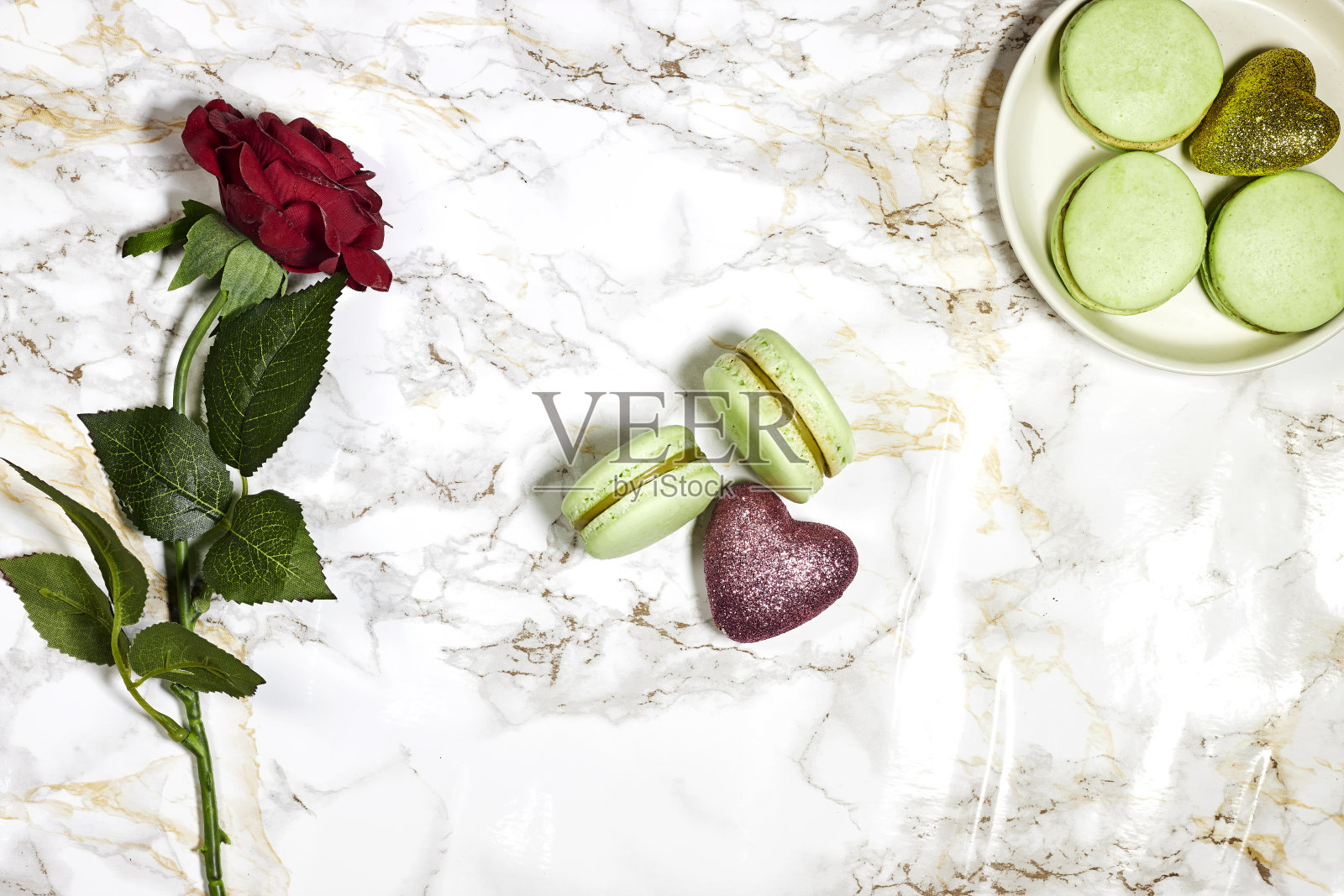 法国开心果马卡龙与红玫瑰花和心闪闪发光的大理石背景照片摄影图片