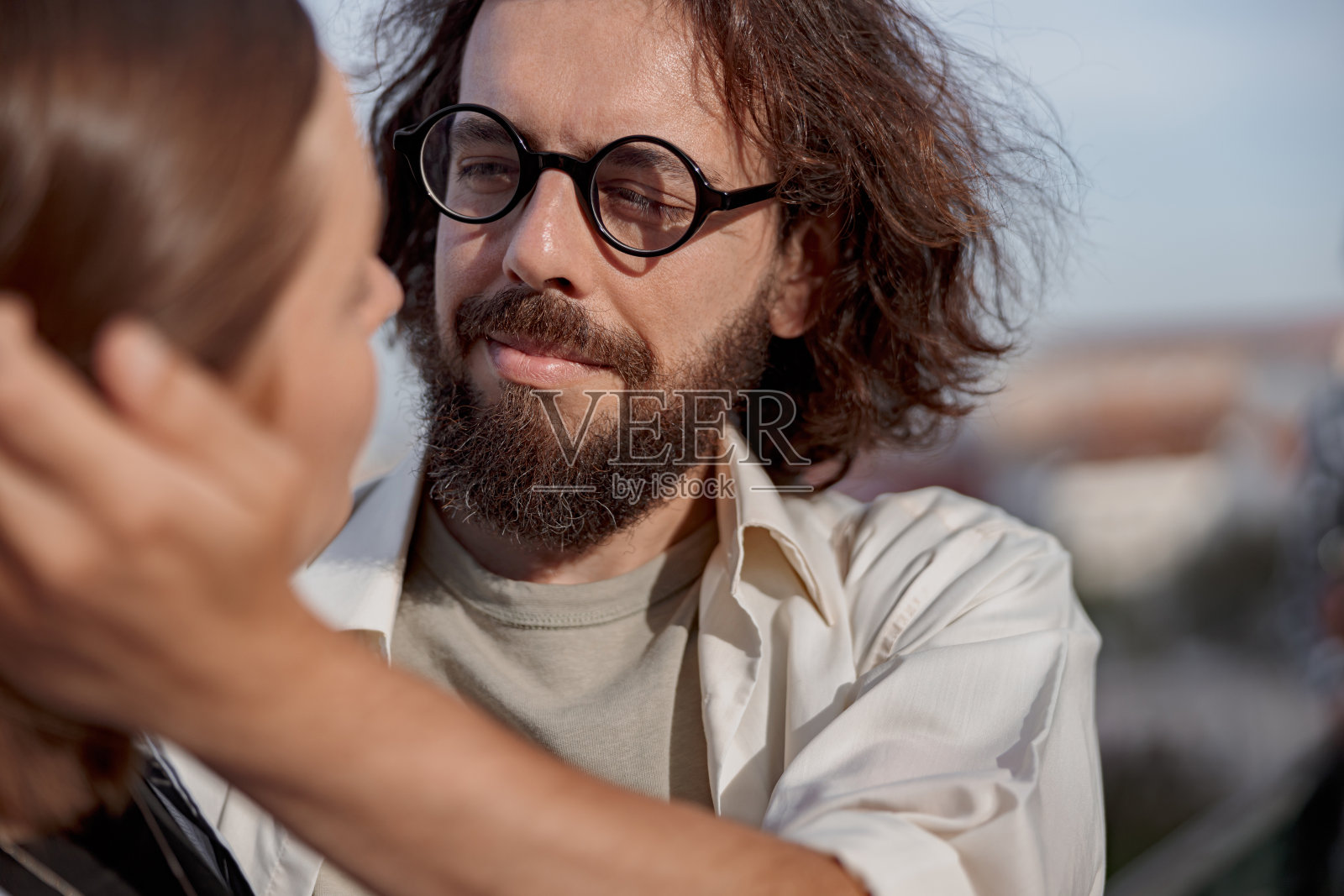 在外面的浪漫约会中，微笑的男孩热情地抚摸着女孩的头发。热恋中的幸福夫妻照片摄影图片