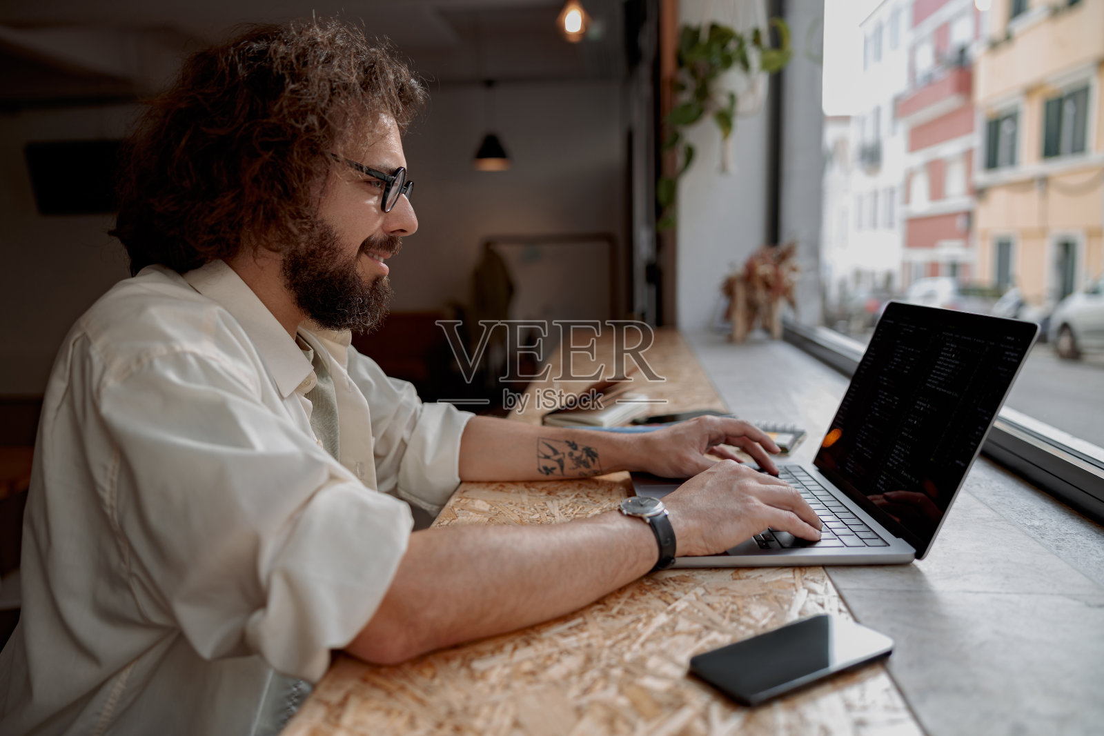 微笑的男性自由职业者坐在现代联合办公的笔记本电脑上工作。远程工作概念照片摄影图片