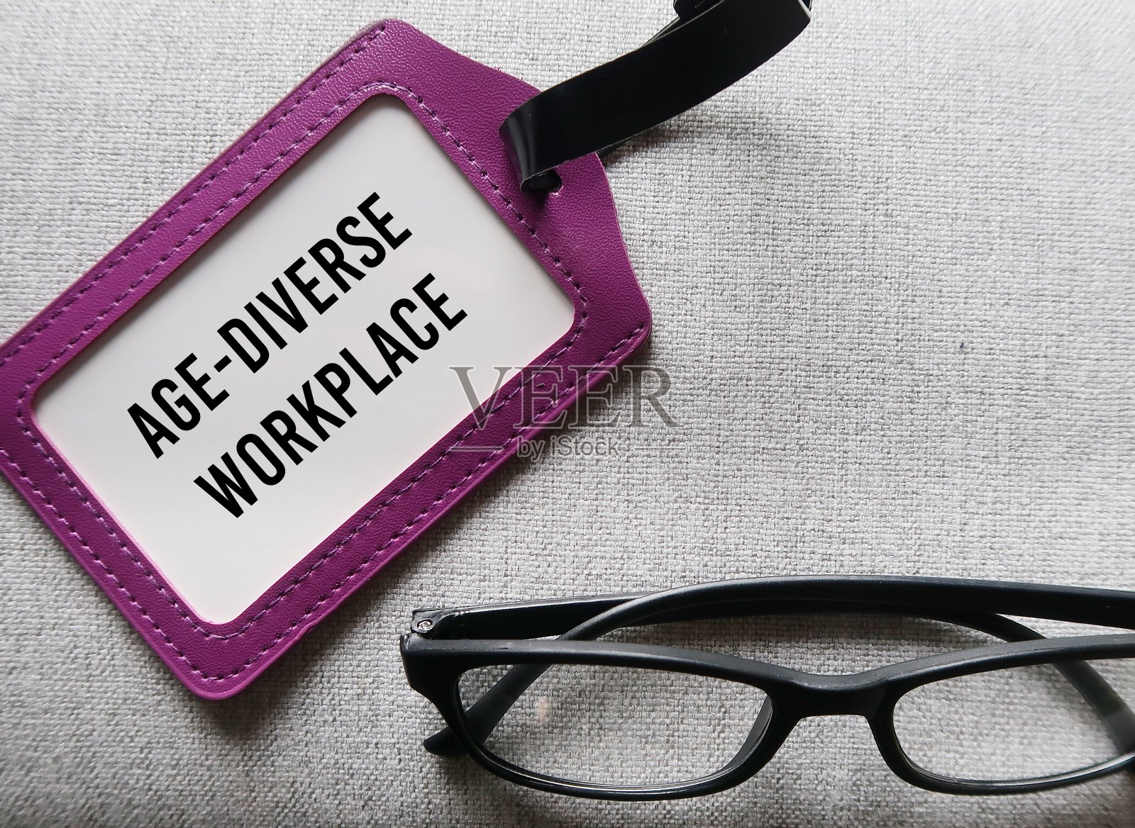 带有age - diverse WORKPLACE字样的老花镜和办公室身份证，指的是办公室或组织中的多代员工和年龄多样化的环境照片摄影图片