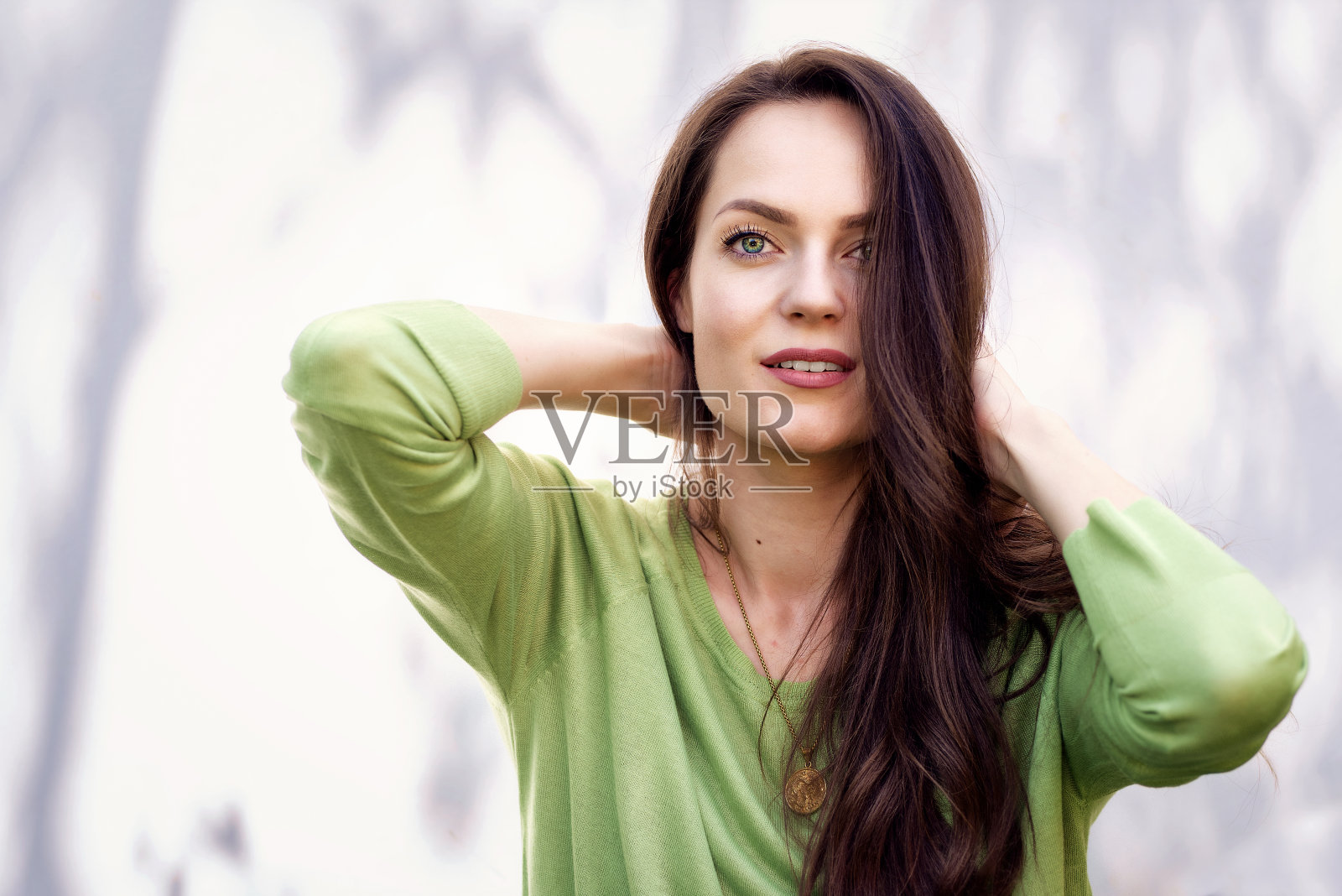 一幅年轻女子的肖像，她有着美丽的绿眼睛和深褐色头发，坐在阳光下照片摄影图片