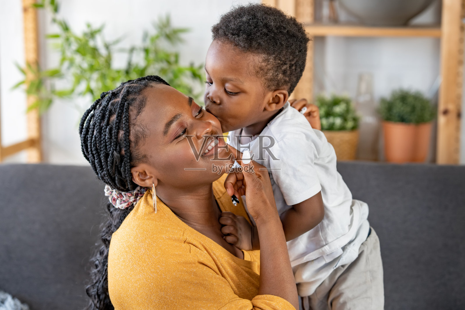 开朗的非裔美国母亲和儿子在家里拥抱，笑着，玩得开心。家庭团聚时间。母亲节照片摄影图片