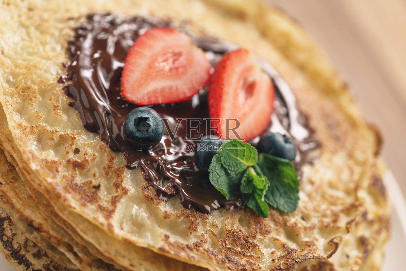 一叠可丽饼，上面撒上浆果和黑巧克力照片摄影图片