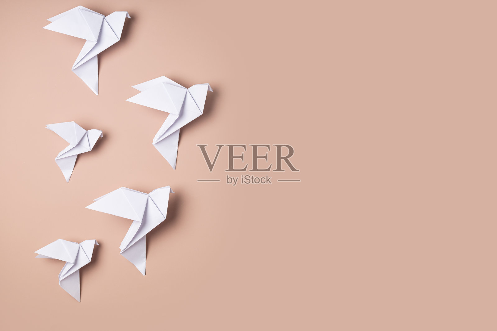 白鸽折纸，作为和平的象征在粉红色的背景上照片摄影图片