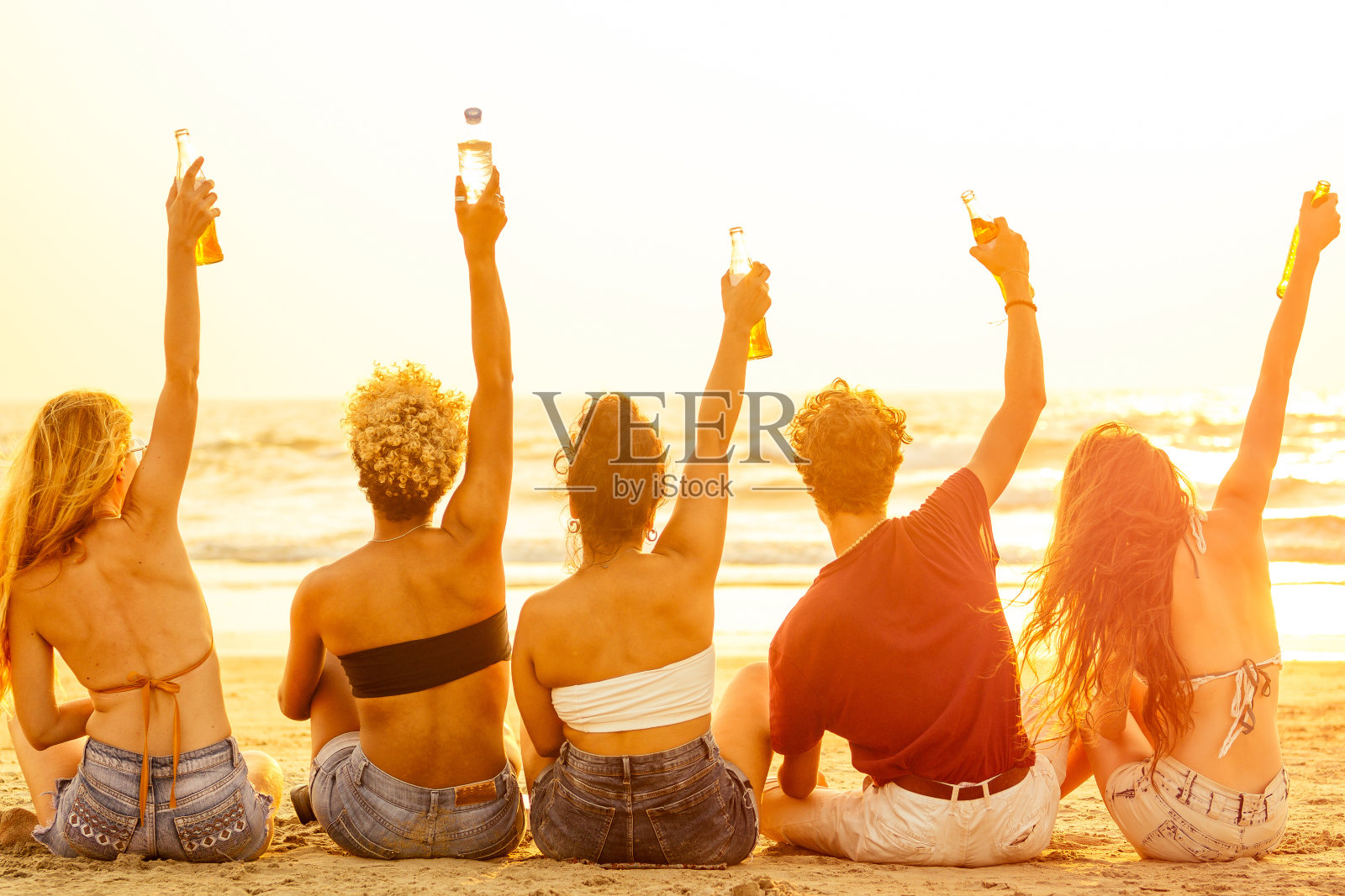 快乐的国际朋友喝果汁从玻璃瓶在海滩上照片摄影图片
