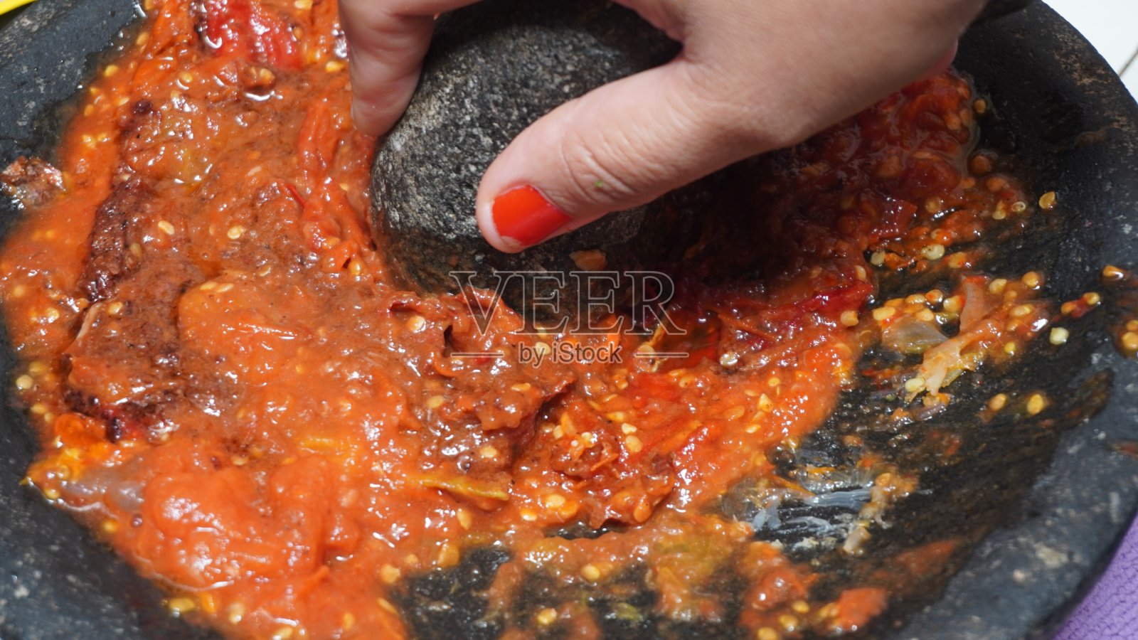 主妇的手正在用石杵磨辣椒和辣椒酱的调味料照片摄影图片