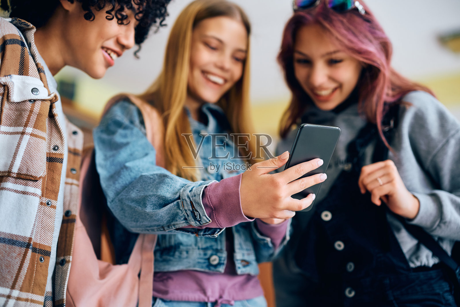 快乐的青少年在学校使用智能手机的特写。照片摄影图片