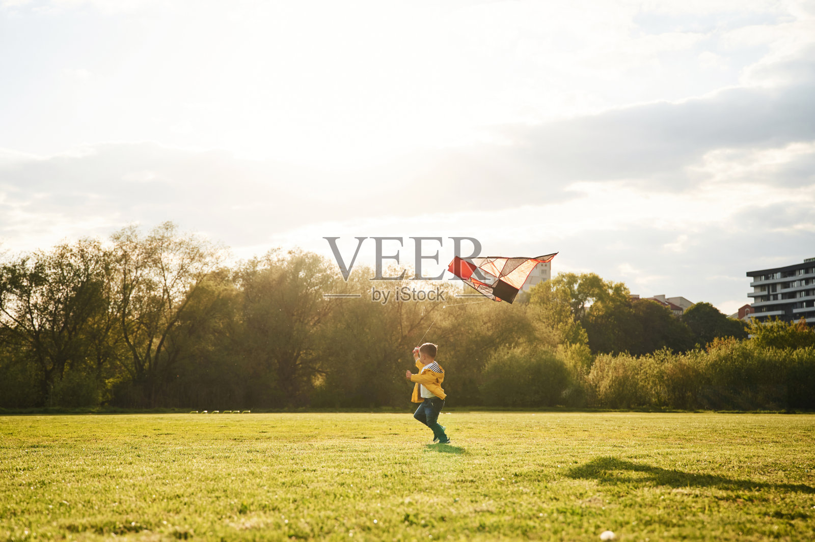 遥远的视图。夏天，一个小男孩在操场上玩风筝照片摄影图片