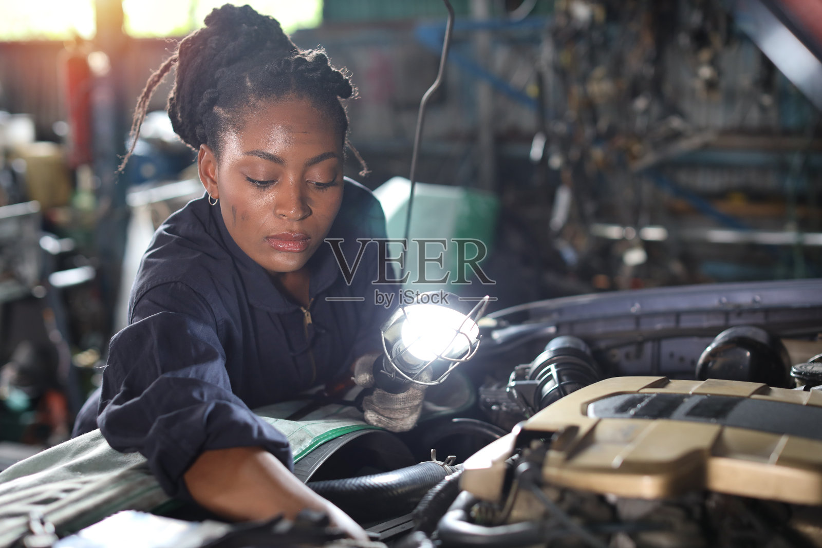 穿制服的女技师在修车站检查保养车服务。工人拿着手电筒和扳手修理损坏的车辆。汽车中心维修服务理念。照片摄影图片