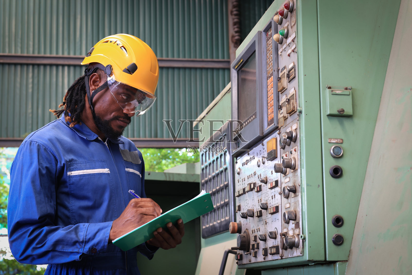 工厂工人正在用平板电脑给数控铣床编程。照片摄影图片