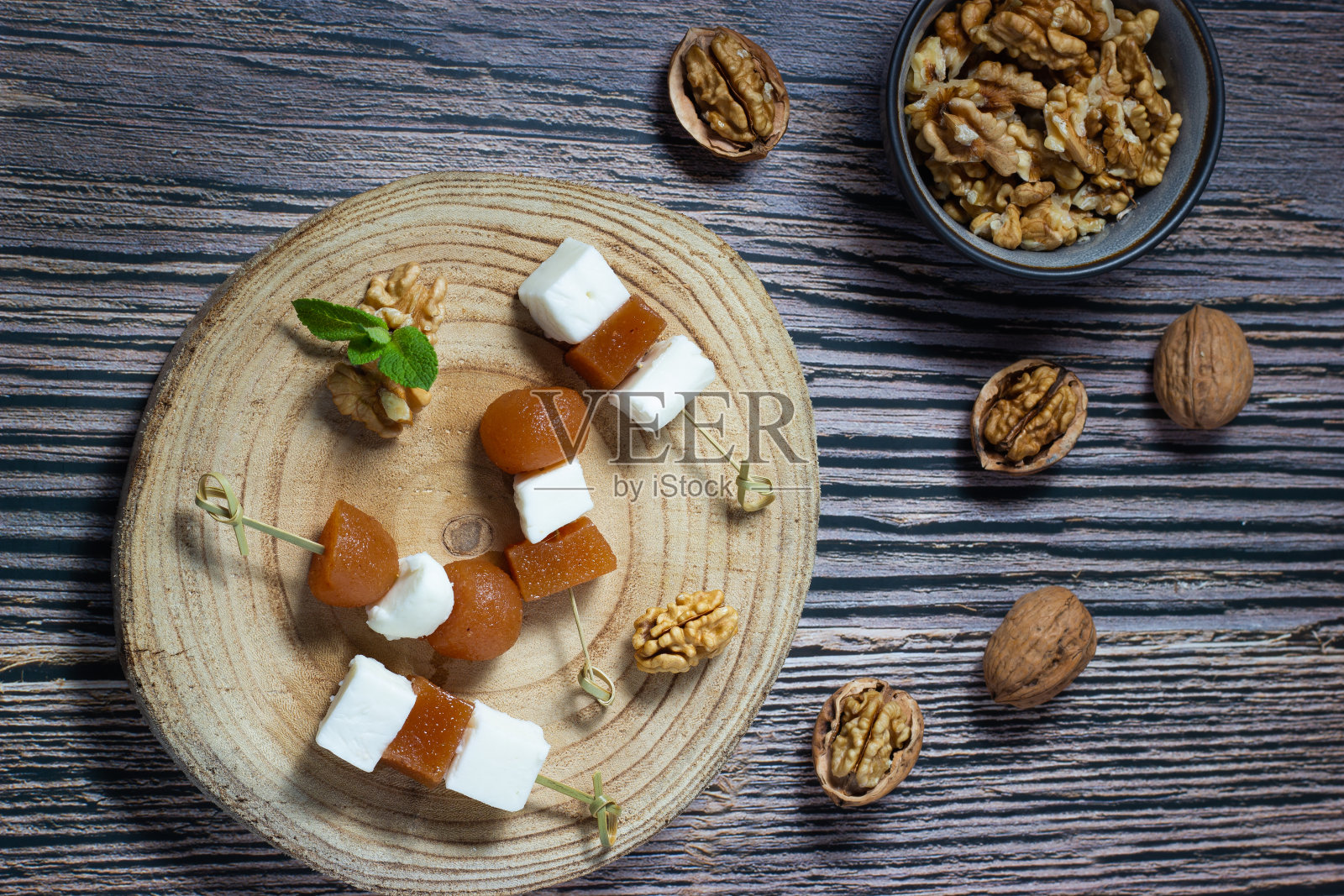 开胃菜有新鲜的山羊奶酪和核桃温黄瓜酱，木质背景。健康的烹饪。照片摄影图片