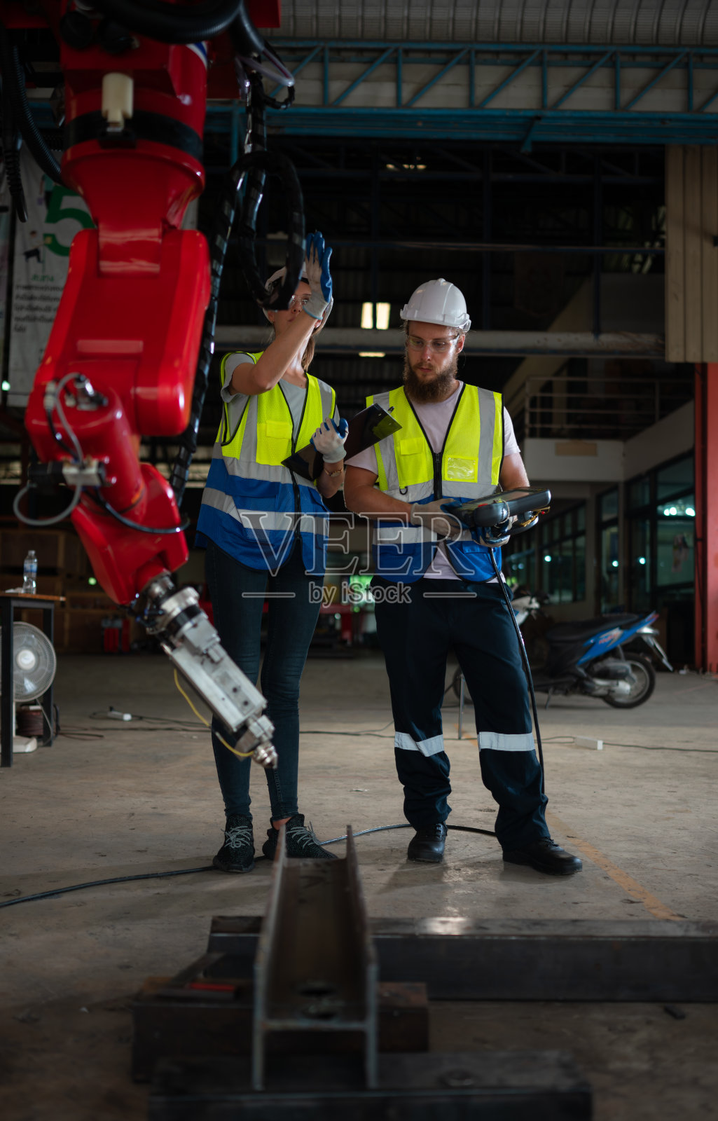 两位工程师都在安装和测试一个大型机械臂。在发送给客户在行业中使用之前照片摄影图片