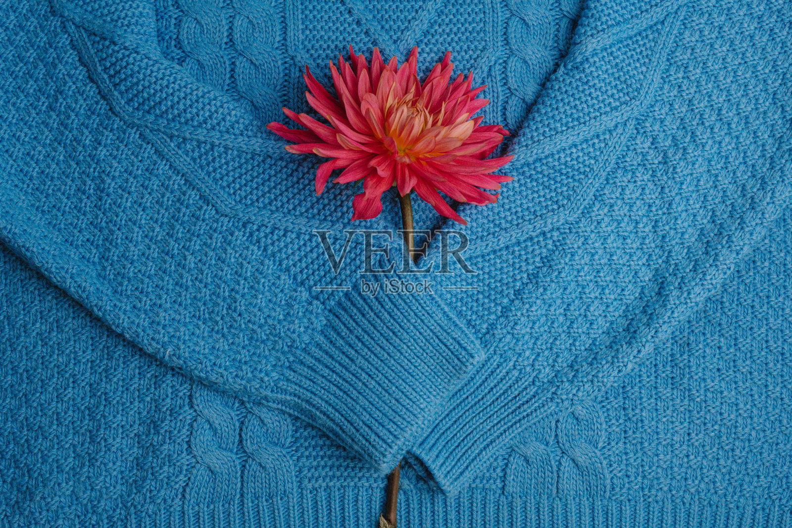 彩色针织毛衣的图案特写。手工美利奴羊毛产品。一叠叠着的衣服和鲜花。照片摄影图片