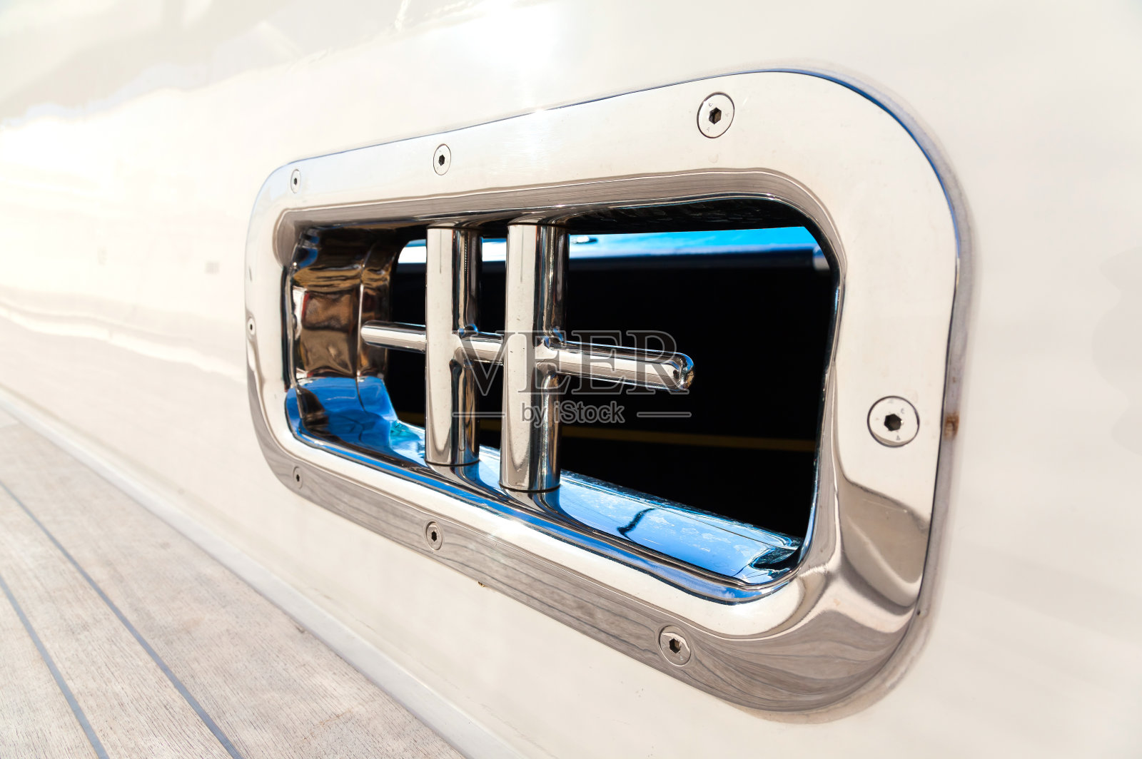 游艇白色船体上的不锈钢系泊柱。照片摄影图片