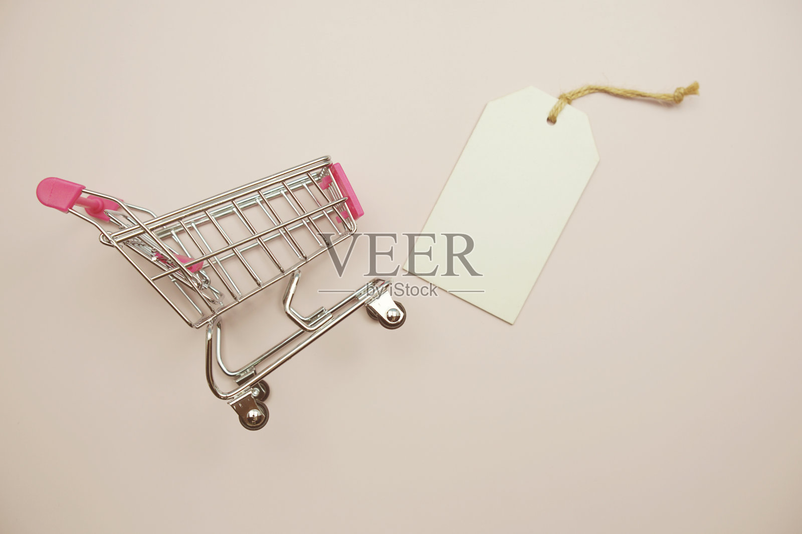 粉红色背景的价格标签和购物车照片摄影图片