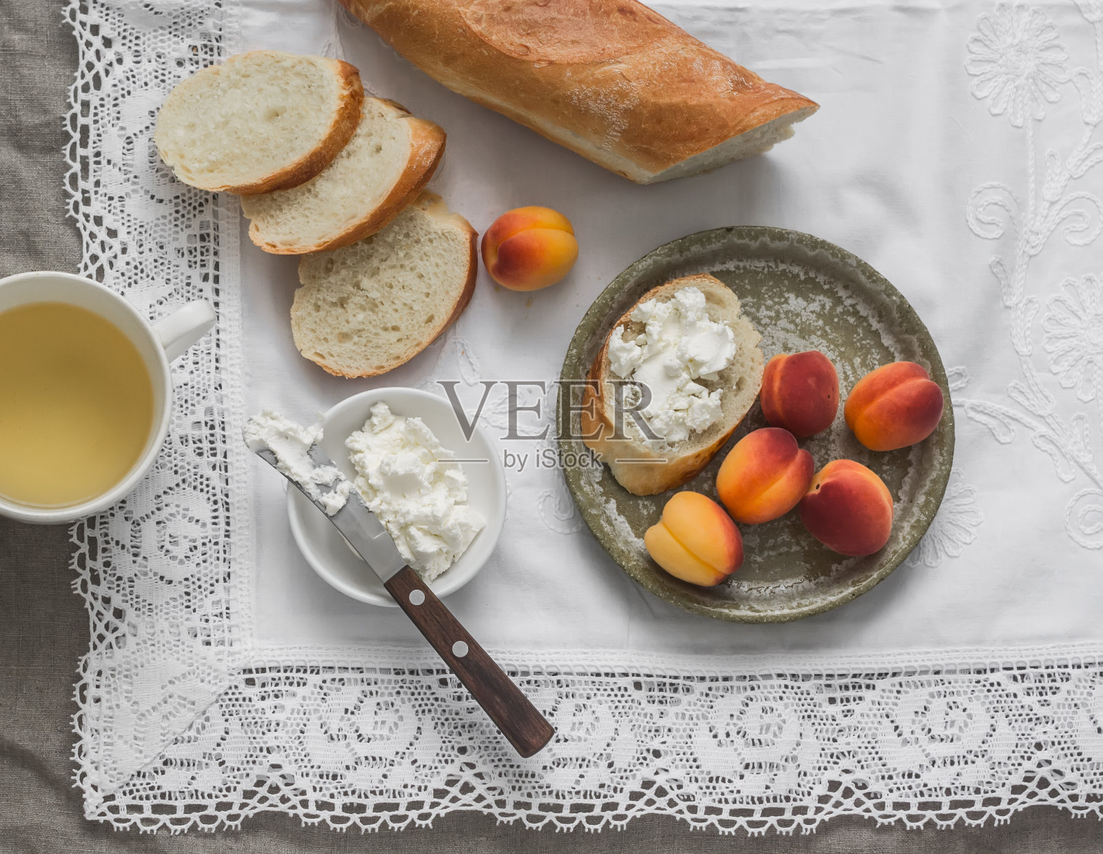 简单的早餐，零食-白干酪，新鲜脆皮法棍和杏子在浅色背景，俯视图照片摄影图片